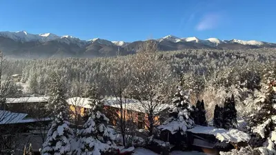 a house covered in snow with mountains in the background at Vista Villa at Katarino SPA in Bansko