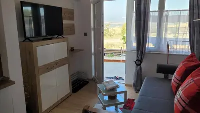 a living room with a couch and a tv on a cabinet at Strumyani tiny flat in Sandanski