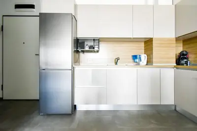 a stainless steel refrigerator in a kitchen with white cabinets at Nomad Friendly Modern Complex Next to Metro in Sofia