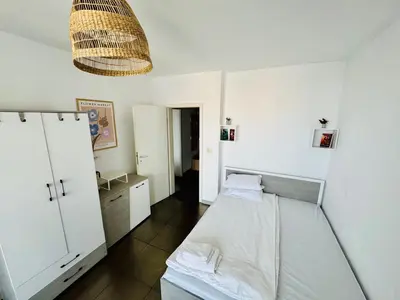 a small bedroom with a bed and a chandelier at New Two Bedroom apartment with balcony in Sofia