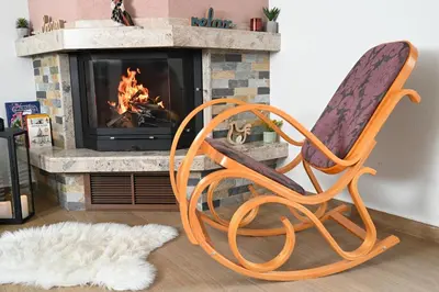an orange rocking chair in front of a fireplace at Стаи за гости Ингилизовата къща in Padala