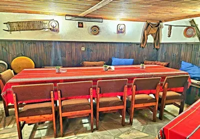 a large red table with chairs and a cat sitting on top at Хотел Механа Воденицата in Zlatkov Chiflik