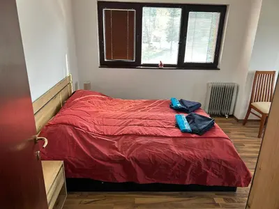 a bedroom with a bed with red sheets and a window at Apartament Armada Bansko in Bansko