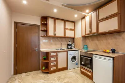 a kitchen with wooden cabinets and a washer and dryer at Апартамент за гости ВениАн in Velingrad