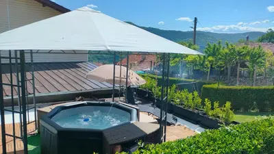 a hot tub with an umbrella in a backyard at Guest House Saint George in Vukovo