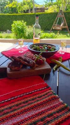 a table with a plate of meat and a bowl of salad at Guest House Saint George in Vukovo