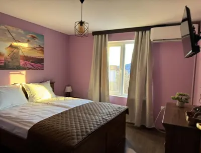 a bedroom with a bed with purple walls and a window at Guest House Saint George in Vukovo