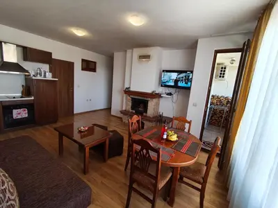 a living room with a table and a room with a fireplace at Apartment Danik River Glaznel in Bansko