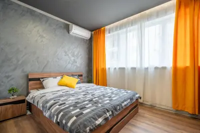 a bedroom with a bed and a window with orange curtains at Cozy Homes 4 in Sofia