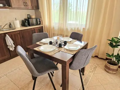 a dining room table with chairs and a table and a kitchen at Cozy apartment in luxury SPA resort St Ivan Rilski Bansko -free wellness & parking- in Bansko