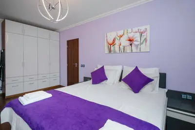 a bedroom with a large white bed with purple pillows at Feel at Home - Central 2BD Flat with Parking by Flat Mаnager in Sofia