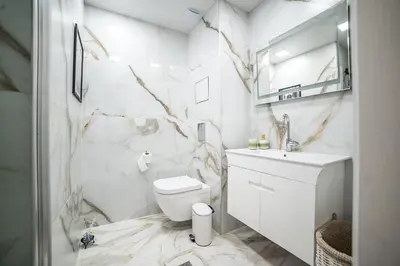 a white bathroom with a toilet and a sink at Lux Apart Karlovo 1 in Karlovo