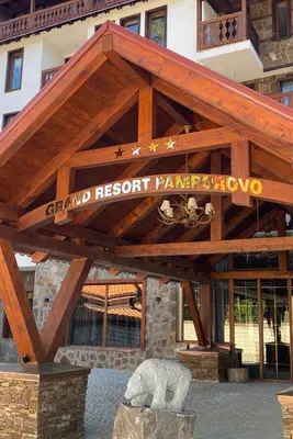 a sign for a resort with a bear statue in front of a building at Pamporovo mountain apartment in Pamporovo