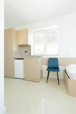 a kitchen with a blue chair next to a bed at Millennia Hotel in Sofia