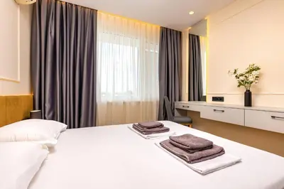 a bedroom with a white bed with towels on it at Sunset 2BR Apartment Central Street PARKING Included in Plovdiv