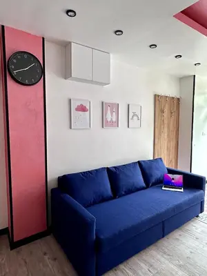a blue couch in a living room with a clock at The rainbow 9 in Sofia