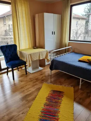 a room with a bed and a table and a chair at Cozy studio with balcony in Sofia