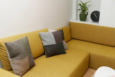 a yellow couch with three pillows on it at Dom Knipituga in Sofia