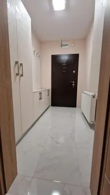 a hallway with a black door and a white tile floor at Апартаменти Недялкови I in Sandanski