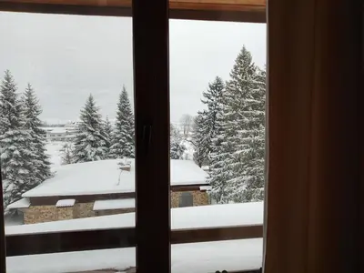 a view of a snow covered yard from a window at Роси Студио Банско in Bansko