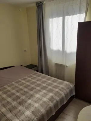 a bedroom with a bed and a window with a plaid blanket at Easy rooms in Sapareva Banya