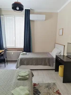 a bedroom with two beds and a desk and a window at EL apartment in Sofia