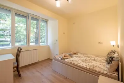 a bedroom with a bed and a desk and windows at Top Location, Brand New 3 BDRM Apt & Free parking in Sofia