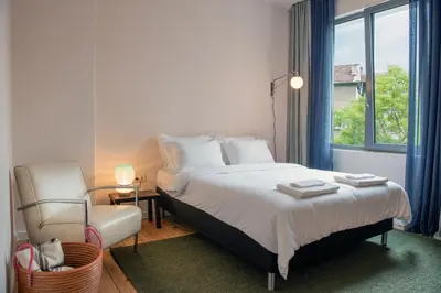 a bedroom with a bed and a chair and a window at Dazzling Minimalist One Bedroom Apartment in Sofia