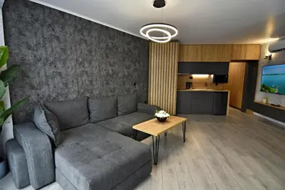 a living room with a gray couch and a kitchen at Апартамент Жери in Velingrad