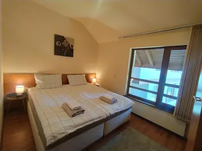 a bedroom with a bed and a large window at Cozy flat in NEON in Bansko