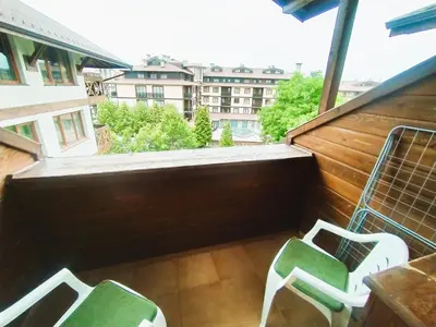 a balcony with two green chairs and a building at Cozy flat in NEON in Bansko
