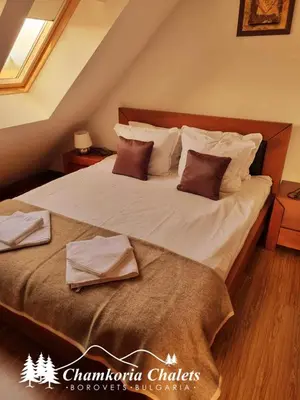 a bedroom with a large bed with white sheets and pillows at Chamkoria Chalets 409 in Borovets