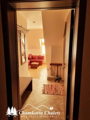 a hallway with a living room with a red couch at Chamkoria Chalets 409 in Borovets