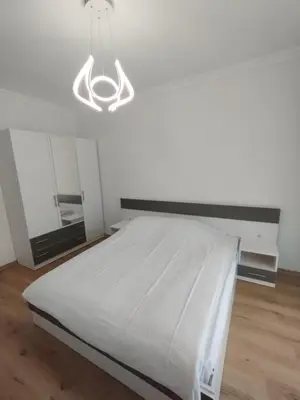 a white bedroom with a bed and a chandelier at Stylish apartment Zingara 2 in Sofia