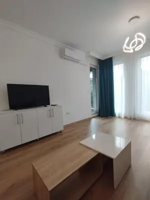 a living room with a table and a flat screen tv at Stylish apartment Zingara 2 in Sofia