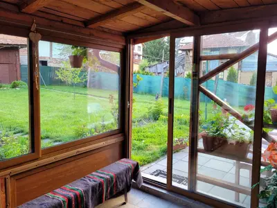 a screened in porch with a bench in front of a window at Къща за гости ЕВА in Madzhare