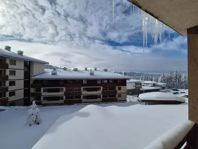 a view of a building in the snow with icicles at Saphir apartment , Rhodopi Pearl Pamporovo in Pamporovo