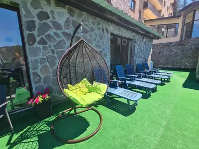 a swing on a patio with chairs and a building at Saphir apartment , Rhodopi Pearl Pamporovo in Pamporovo