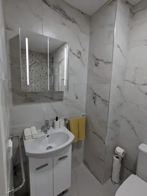 a white bathroom with a sink and a mirror at Reina Apartment- next to Sofia zoo and close to Mall Paradise in Sofia
