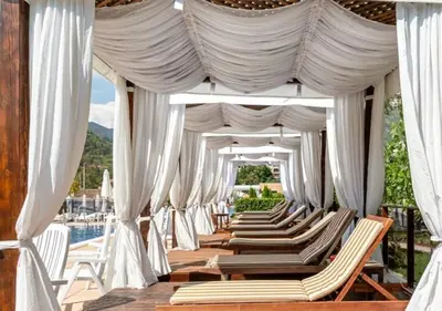 a row of lounge chairs under a canopy at a pool at Парк Хотел Модър in Devin
