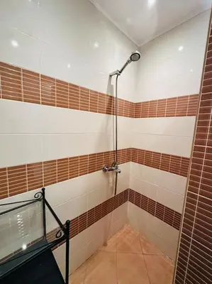 a bathroom with a shower with brown and white tiles at Student Town 1BDR APT in Sofia