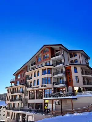 a large apartment building with snow in front of it at The Bear Pamporovo in Pamporovo