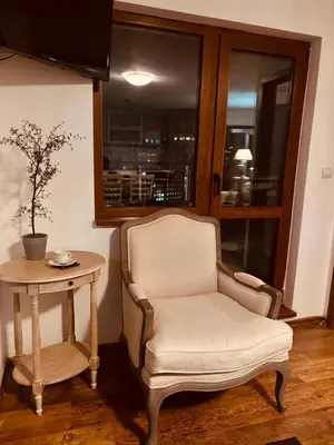 a chair and a table in a room with a window at Spacious apartment with a Mountain view, big balcony and parking in Sofia