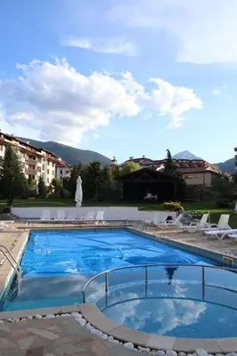 a large swimming pool with chairs and a building at Lux apartment 223 in Bansko
