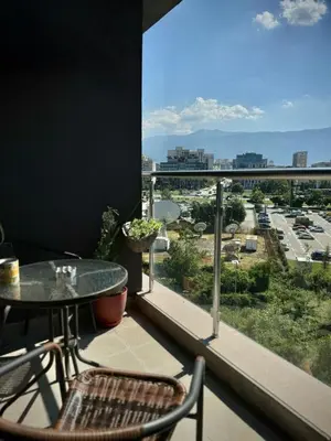a balcony with a table and chairs and a view of a city at Sunny & Comfort Apartment next to Tech Park for 4 Guests in Sofia