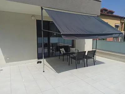 a patio with chairs and a table with a blue umbrella at Sunshine terrace in Plovdiv