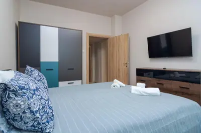 a bedroom with a blue bed and a flat screen tv at Spacious Sofia Condo - Philadelphia LOVE in Sofia