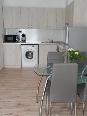 a kitchen with a table and chairs and a washing machine at Апартамент Престиж 1 in Hisarya