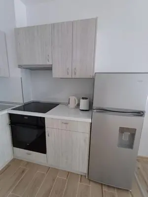 a small kitchen with white cabinets and a refrigerator at Апартамент Престиж 1 in Hisarya