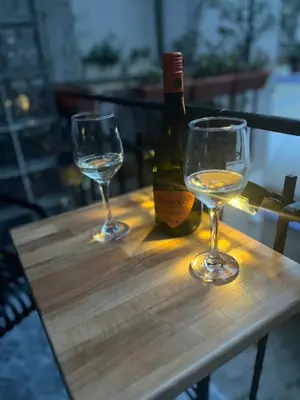 two wine glasses on a wooden table with a bottle of wine at Sofia Vibes - Friends & Family Stay in Sofia